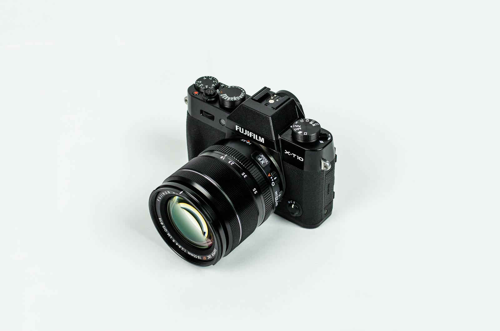 Close-up of a Fujifilm camera with lens on a plain background, showcasing photographic equipment.